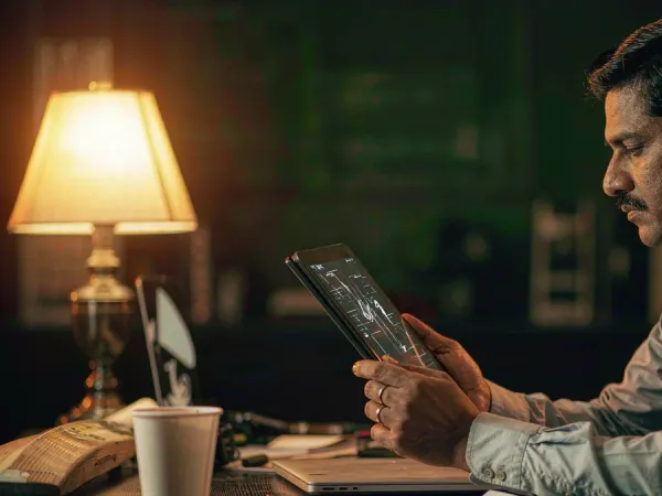 six6s + Man studying a match-data interface on a tablet beside a bat and coffee