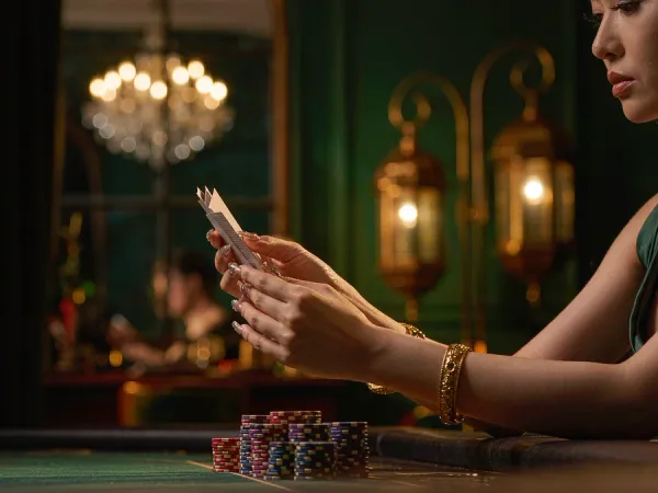 six6s + Hands with gold bangles holding three cards beside chip stacks