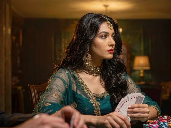 six6s + Woman in teal and gold holding cards at a chip-stacked poker table