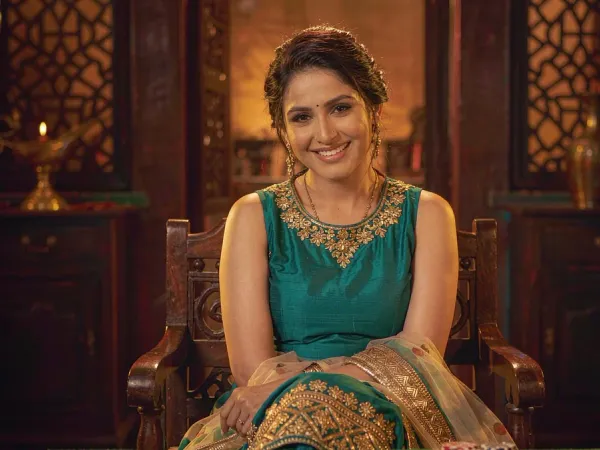 six6s + Woman in teal and gold smiling at three cards on a green table